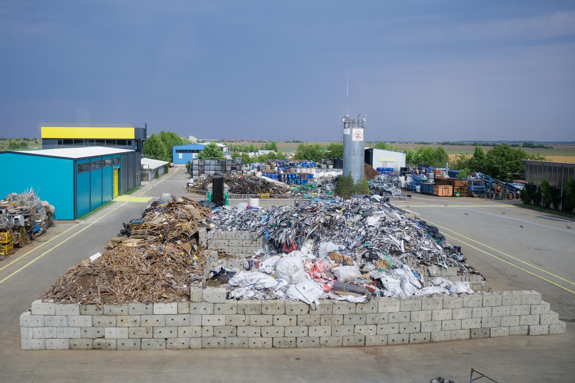 Aerial view of the KUPELO site with sorted wood, metal and plastic waste in concrete bays and industrial halls